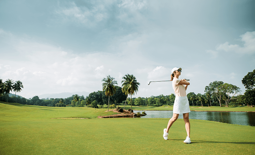 Female golfer in action on green field